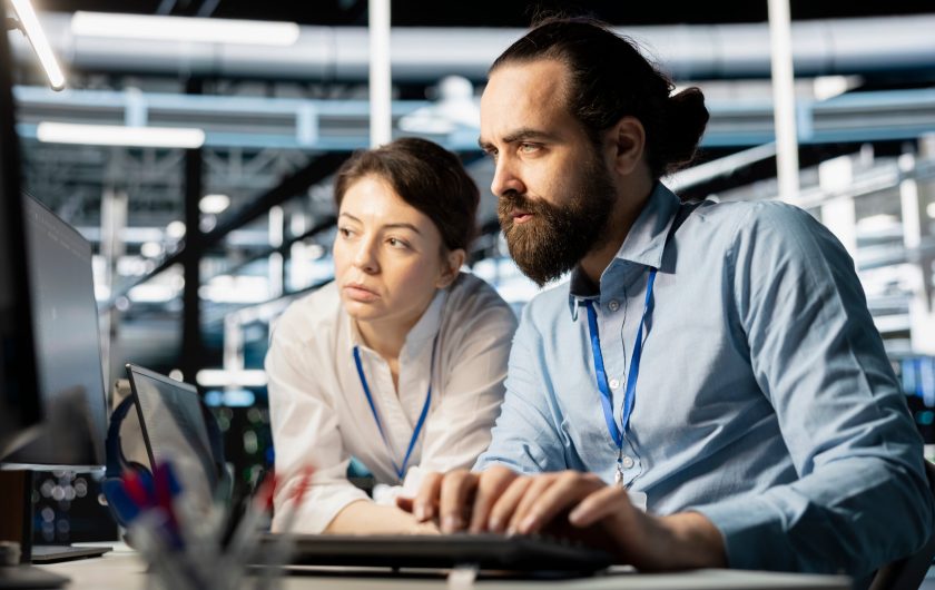 Data center coworkers doing brainstorming, running diagnostic scripts on computer, examining hardware. Server room employees talking, working together to evaluate performance metrics