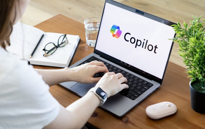 Poznan, Poland - June 15, 2025: Copilot AI assistant software displayed on a modern laptop, with user hands actively typing on keyboard, emphasizing digital productivity and innovation
