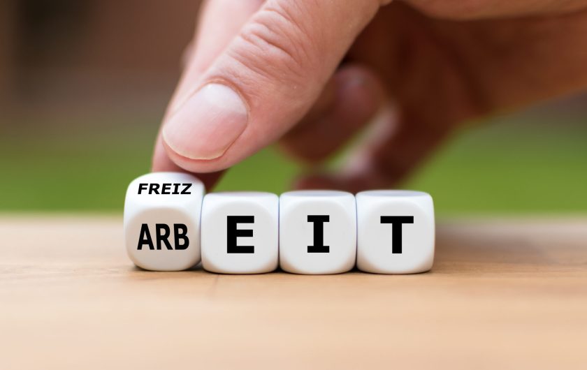 Hand dreht einen Würfel und ändert das Wort „Arbeit“ in „Freizeit“. Hand dreht einen Würfel und ändert das Wort "Arbeit" in "Freizeit".