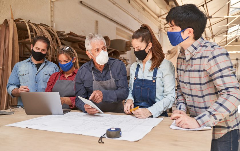 Handwerker Team mit Mundschutz wegen Covid-19 in einer Besprechung