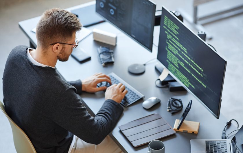 High angle view at software developer writing code while using computer and data systems in office